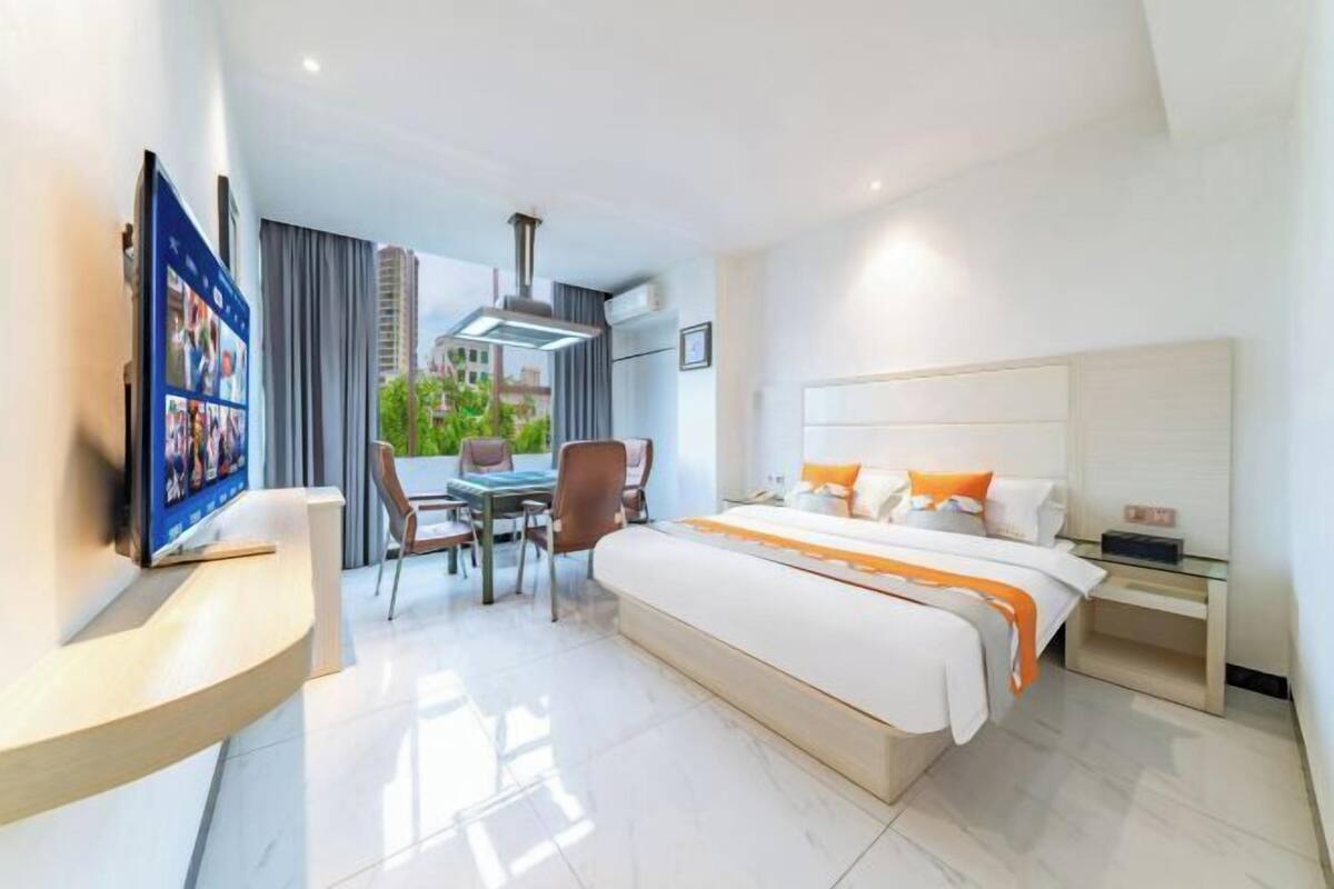 A hotel room with a bed, bedside table, TV, and a balcony with a view.
