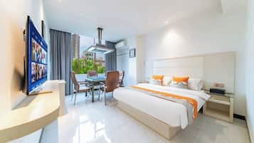 Habitación de hotel con cama, mesita de noche, televisor y balcón con vistas.