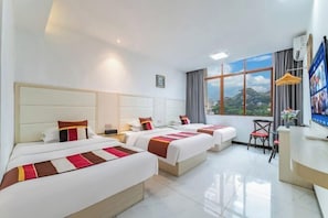 A hotel room with three beds, a desk, and a large window with a view. - Fuli Business Hotel (Chengmai)