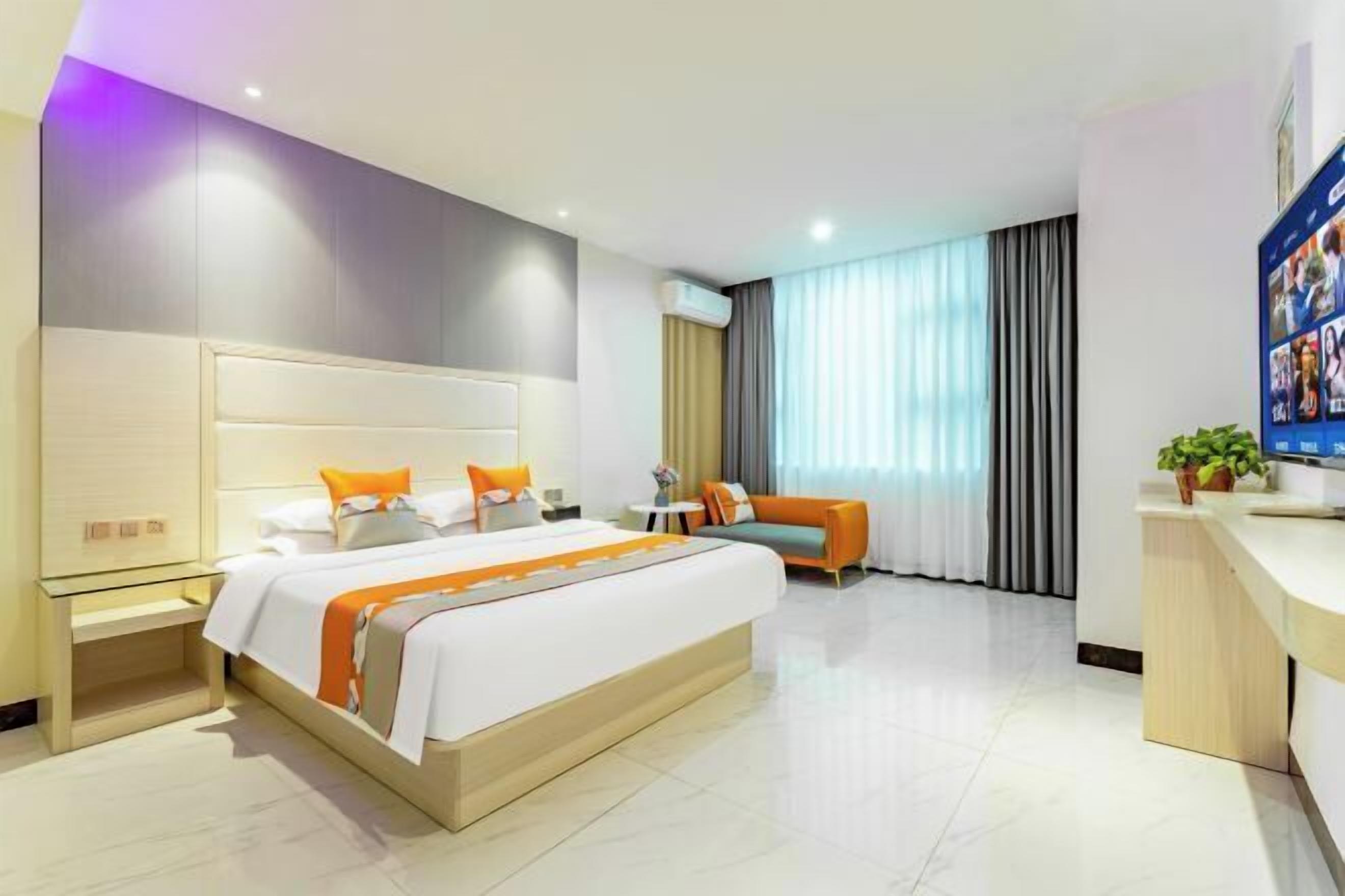 A hotel room with a large bed, a sofa, a desk, and a TV.