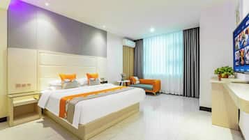 Una habitación de hotel con una cama grande, un sofá, un escritorio y un televisor.