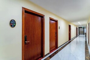 A hotel corridor with wooden doors, a marble floor, and a digital keycard reader. - Fuli Business Hotel (Chengmai)
