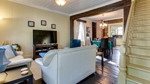 A living room with a sofa, TV, and a dining area with a table and chairs.