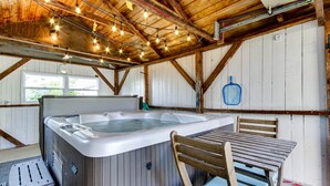 A wooden interior with a hot tub, wooden table, and chairs.