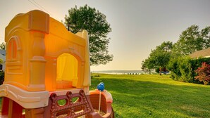 A children's play structure in a grassy area with a clear view of the sky and distant landscape.