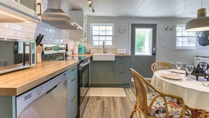 Una cocina moderna con encimera de madera, electrodomésticos integrados y un área de comedor con una mesa dispuesta para dos personas.