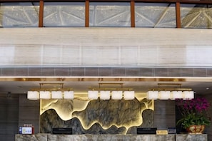 A reception area with a marble counter, a decorative wall, and a ceiling with a geometric pattern.