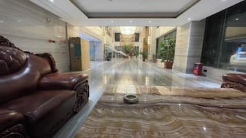 Un vestíbulo de hotel con un mostrador de recepción de mármol, asientos de cuero y vistas del interior.