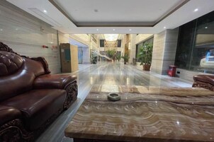 Un vestíbulo de hotel con un mostrador de recepción de mármol, asientos de cuero y vistas del interior.