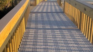 A wooden boardwalk leading to the beach with a patterned metal floor. - Emerald Dream, Oceanside House in Emerald Isle, NC (Emerald Isle)