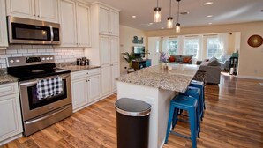 A modern kitchen with white cabinets, stainless steel appliances, and a granite countertop. - Emerald Dream, Oceanside House in Emerald Isle, NC (Emerald Isle)