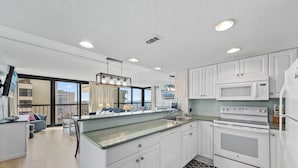 Una cocina moderna con armarios blancos, microondas integrado y una isla grande con pileta.
