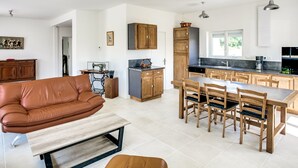 Une cuisine moderne avec des meubles en bois, un coin repas avec une table et des chaises, et un salon avec un canapé en cuir et une table basse.