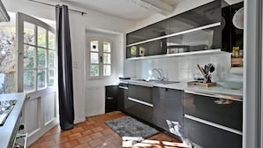Ett modernt kök med ett stort fönster, en svart gardin och ett kaklat golv.