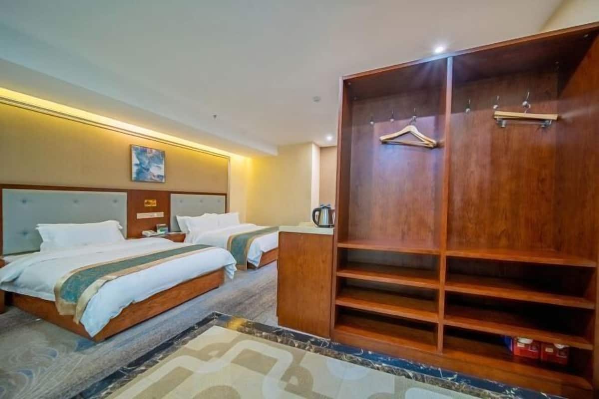 A hotel room with two beds, a wooden wardrobe, and a bedside table.