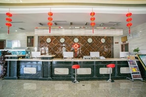 Zona de recepción con mostrador, sillas y un muro decorativo.
