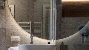 Un baño moderno con un espejo grande, un lavabo blanco y un mueble de tocador de madera.