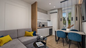 Una sala de estar moderna con un sofá gris, una mesita de centro pequeña y un comedor con sillas azules y una mesa blanca.