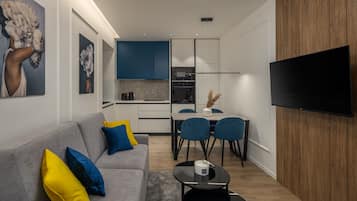 Ein modernes Wohnzimmer mit einem grauen Sofa, blauen und gelben Kissen, einem Couchtisch und einem flachbildfernseher, der an einer Holzwand angebracht ist.
