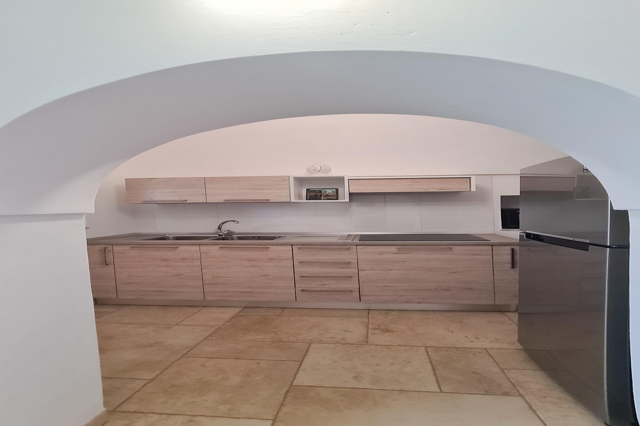 Una cucina moderna con mobili in legno chiaro, un lavello in acciaio inossidabile e un forno integrato.