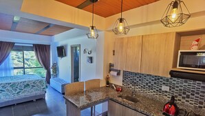 A modern kitchen with a granite countertop, a red kettle, and a microwave. - Descanso bajo la Piedra (Guatapé)