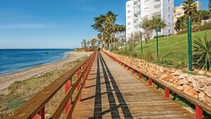 A wooden boardwalk leading to a beach with a white building in the background.
