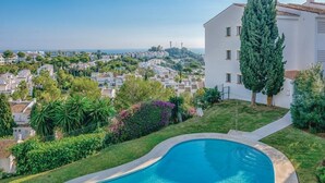 A residential area with a swimming pool surrounded by greenery and a tall tree. - Cosy apartment in Mijas (Mijas)