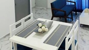 Een gezellige, compacte leefruimte met een eettafel, stoelen, een bank en een deur.