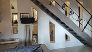 A modern interior with a staircase, a flat-screen TV, a vase, and a radiator. - The Golden Gecko Country House  (Cotignac)