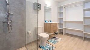 A modern bathroom with a glass shower enclosure, a toilet, a sink with a mirror, and built-in shelving. - Apartment La Désirade - Sainte-Anne (Sainte-Anne)