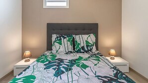 A bedroom with a bed, two bedside lamps, a window, and an air conditioner. - Apartment La Désirade - Sainte-Anne (Sainte-Anne)
