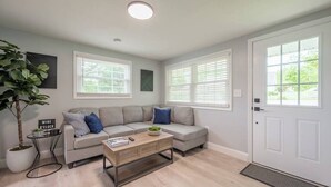 A living room with a grey sofa, a coffee table, and a potted plant. - Modern Home 2 Miles to Virginia Tech (Blacksburg)