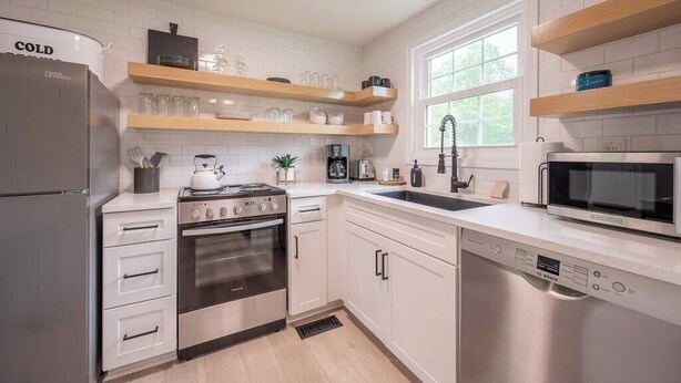 A modern kitchen with white cabinetry, a Bosch dishwasher, a stainless steel refrigerator, and a built-in oven. - Modern Home 2 Miles to Virginia Tech (Blacksburg)