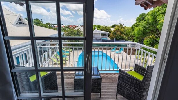 A view from a balcony with wicker furniture and a pool. - Les Saintes in Sainte-Anne (Sainte-Anne)