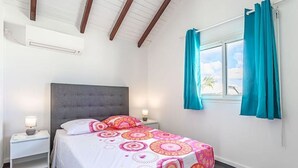 A bedroom with a bed, nightstands, a window with curtains, and a view of the sky. - Les Saintes in Sainte-Anne (Sainte-Anne)
