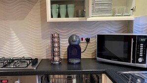 A kitchen with a dishwasher, a microwave, and a cabinet with glassware and plates. - VERY CLEAN + AIR CONDITIONING + PARKING + INTERNET (Manchester)