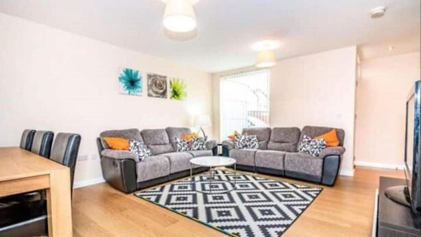 A living room with a grey sectional sofa, a coffee table, and a patterned rug. - VERY CLEAN + AIR CONDITIONING + PARKING + INTERNET (Manchester)