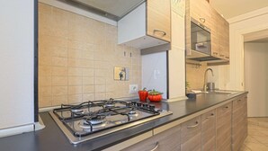 A modern kitchen with a gas stove, wooden cabinets, and a stainless steel range hood.