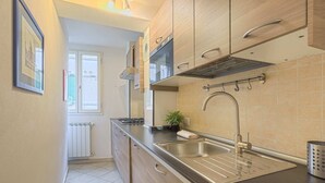 A modern kitchen with wooden cabinets, a stainless steel sink, and a window with blinds.
