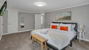 A bedroom with a bed, a bench, a bedside table, a lamp, and a painting on the wall.