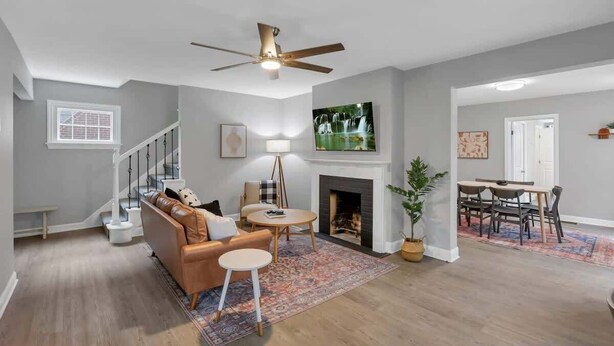 A spacious living room with a fireplace, a dining area, and a staircase.