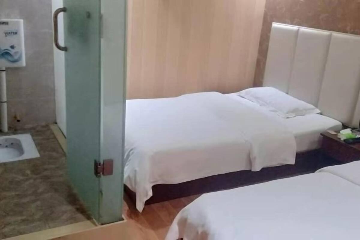 Habitación de hotel con dos camas, un inodoro y dispensador de agua.