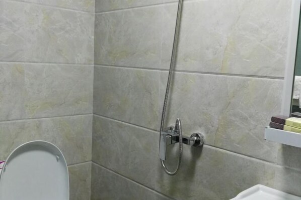 A bathroom with a shower, toilet, and a mirror. - Tashan Hotel (Langzhong)