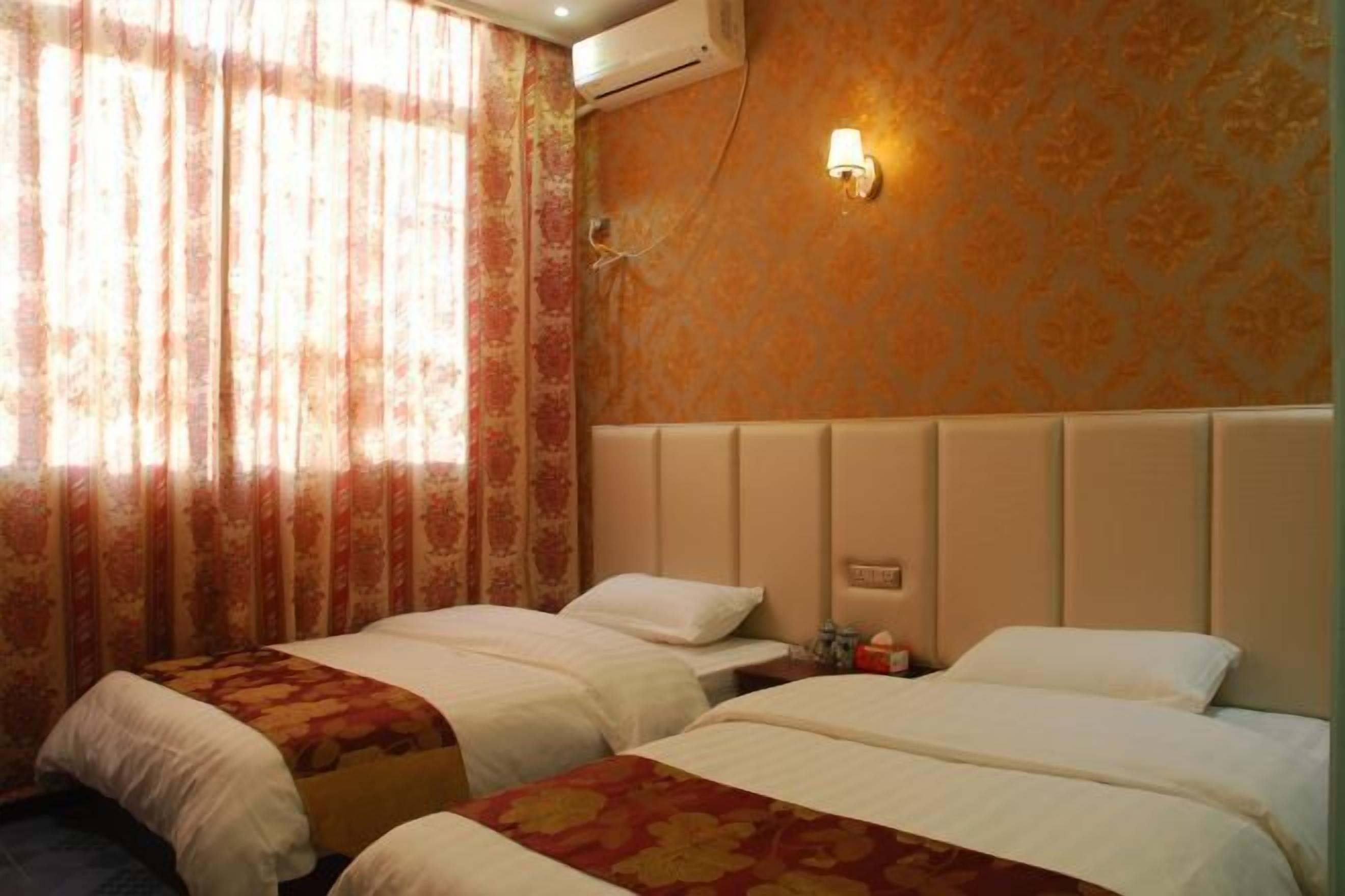 A hotel room with two beds, a wall-mounted air conditioner, and a decorative light fixture.
