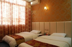 Quarto de hotel com duas camas, ar condicionado fixado na parede e luminária decorativa.
