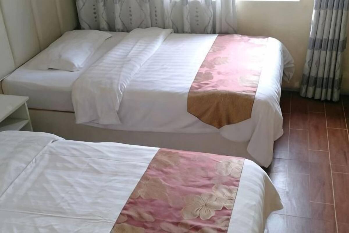 Una habitación con dos camas, una mesita de noche y una ventana con cortinas.
