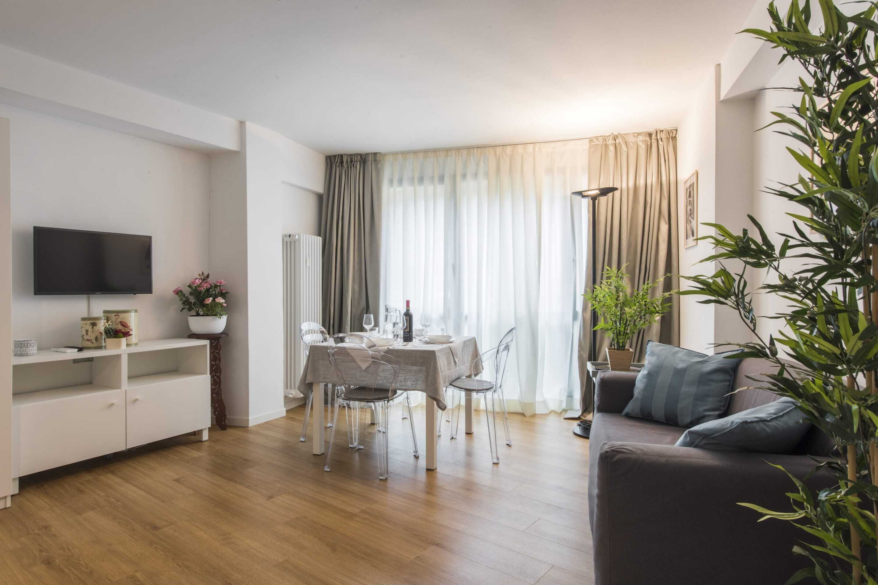 Una sala de estar moderna con comedor, televisor de pantalla plana y sofá.