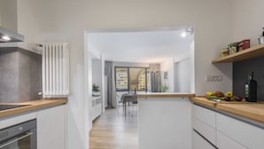 A modern kitchen with white cabinets, a wooden countertop, and a view to a dining area. - Vasari Suite Florence (Florence)