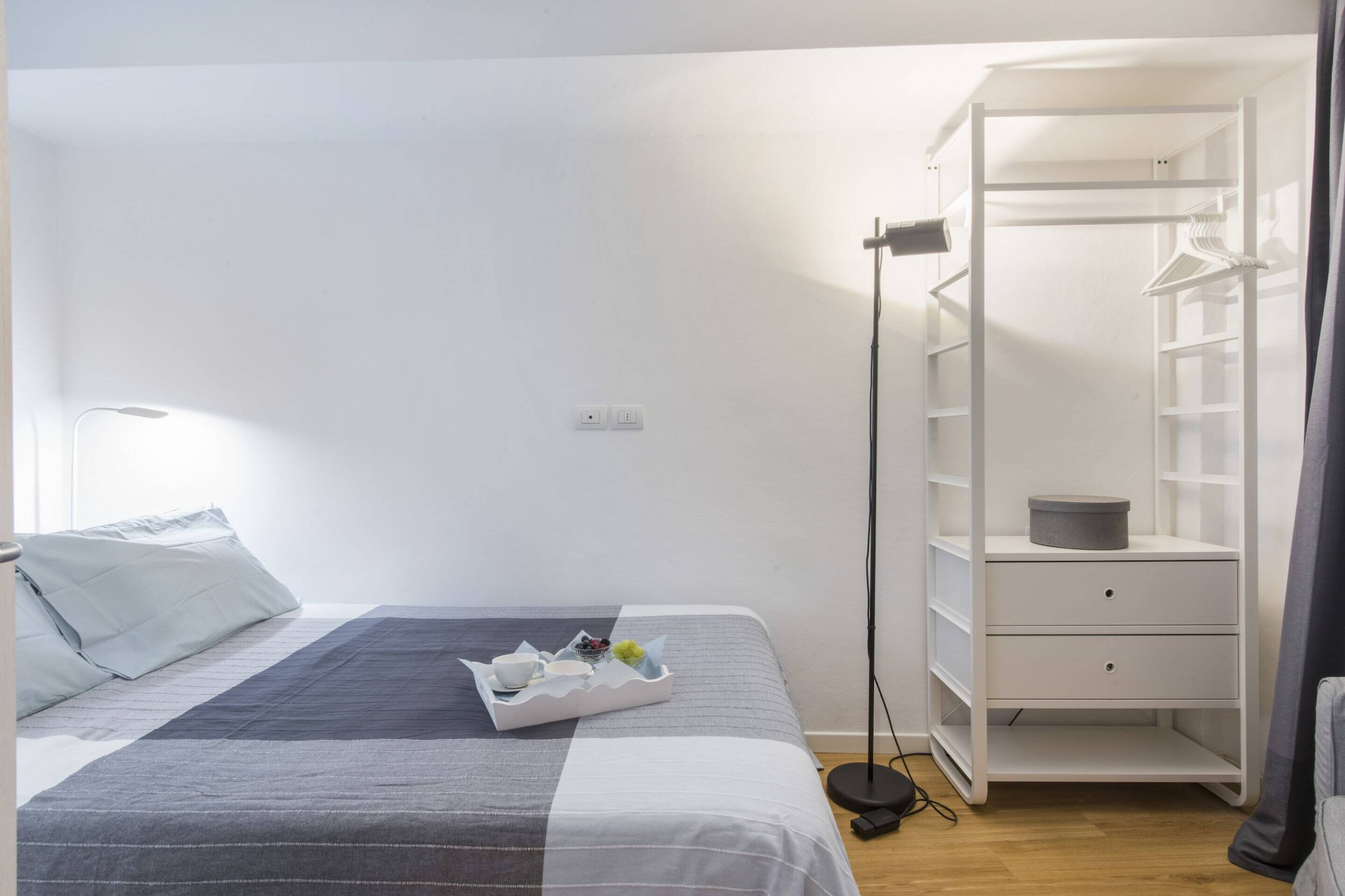 A neatly arranged bedroom with a bed, bedside table, and a wardrobe.