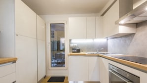 A modern kitchen with white cabinets, a wooden countertop, and stainless steel appliances. - Vasari Suite Florence (Florence)